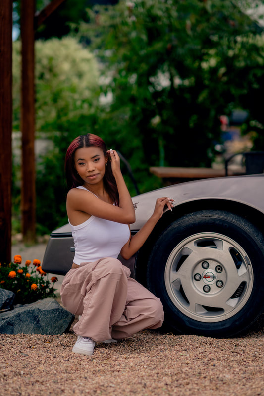 Girl with cargo pants and white tank top sitting next to her car broomfield Colorado senior pictures