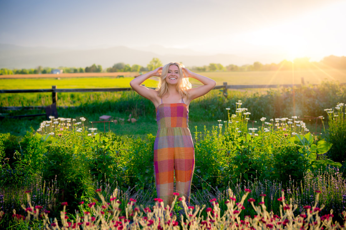 Blonde girl smiling at camera with sun shining behind her for senior pictures