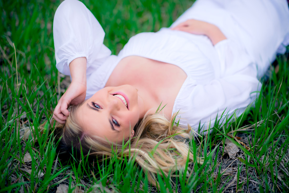 Girl in white dress laying in field for senior pictures 