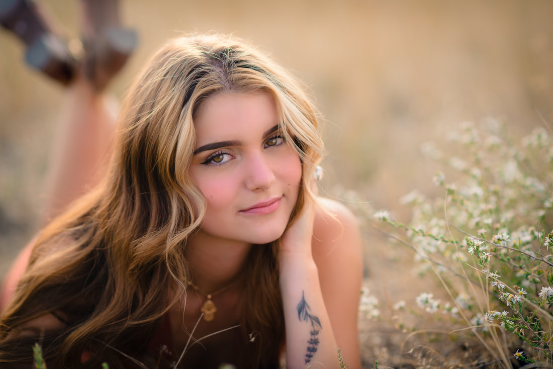 Girl with blonde hair laying in a field of flowers for senior pictures