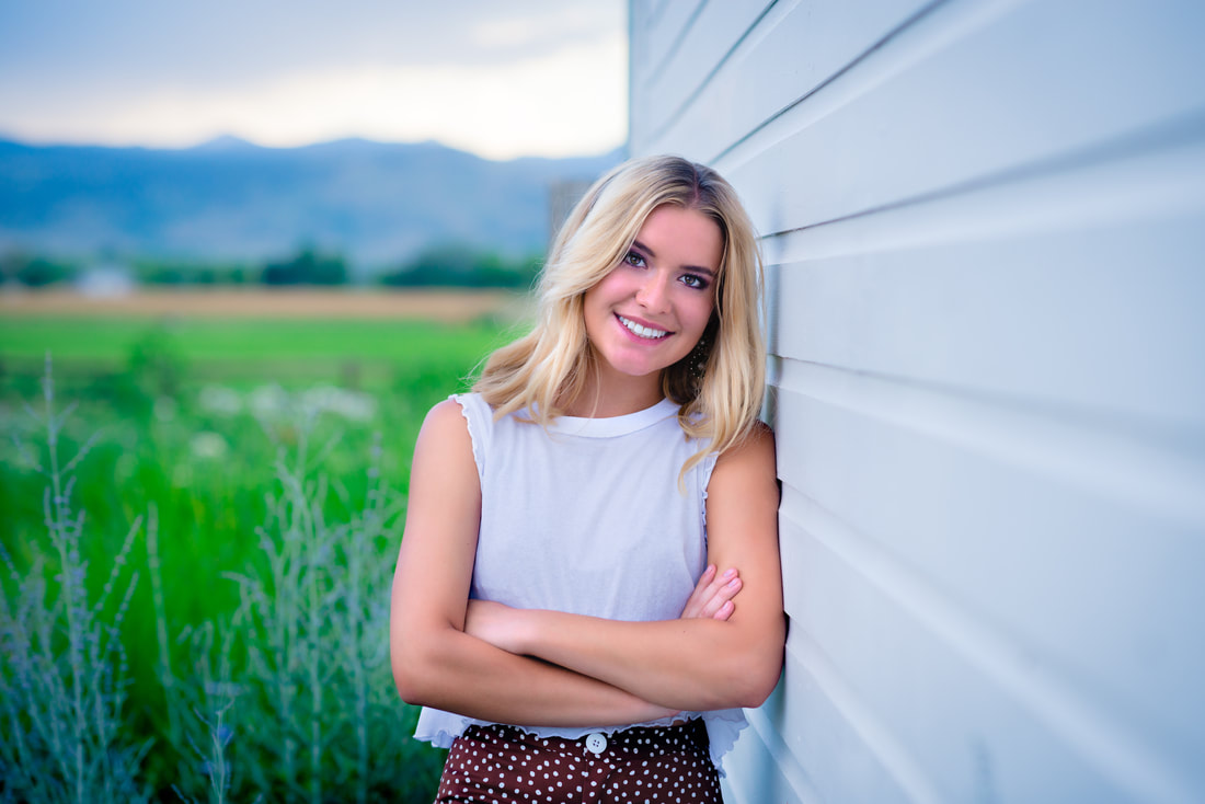 Girl leaning against a white barn for senior pictures