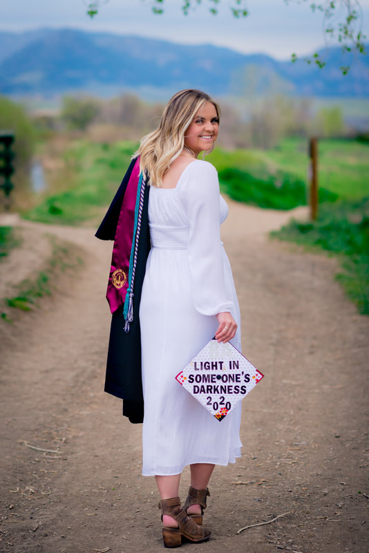 Girl walking away holding graduation cap and gown for senior pictures