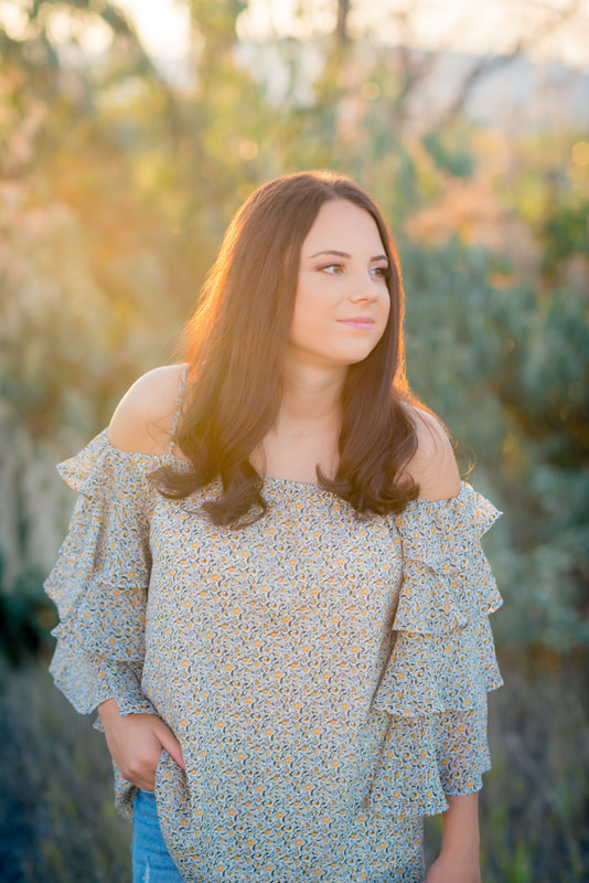 Girl with brown hair senior pictures in floral top with golden sun