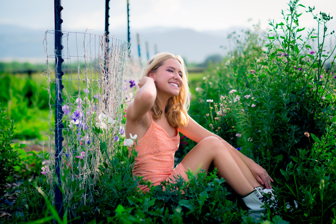 Blonde girl with her eyes closed leaning against a fence for senior pictures 