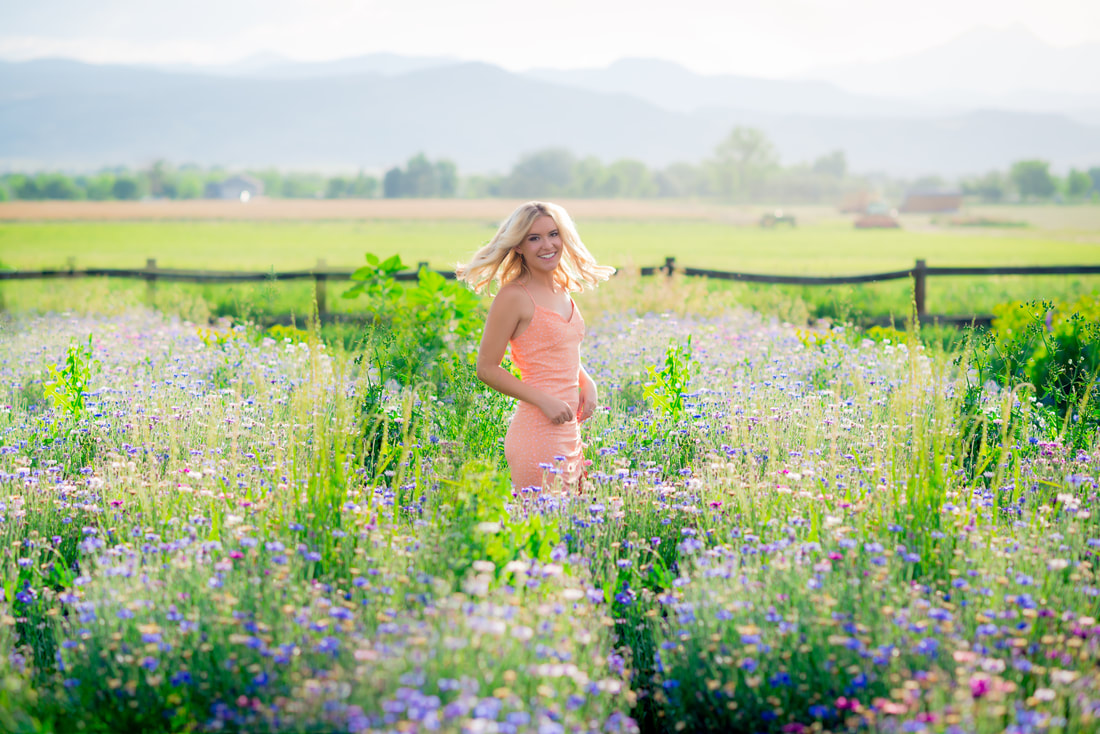 Blonde girl twirling twirling in a field of wildflowers for senior pictures