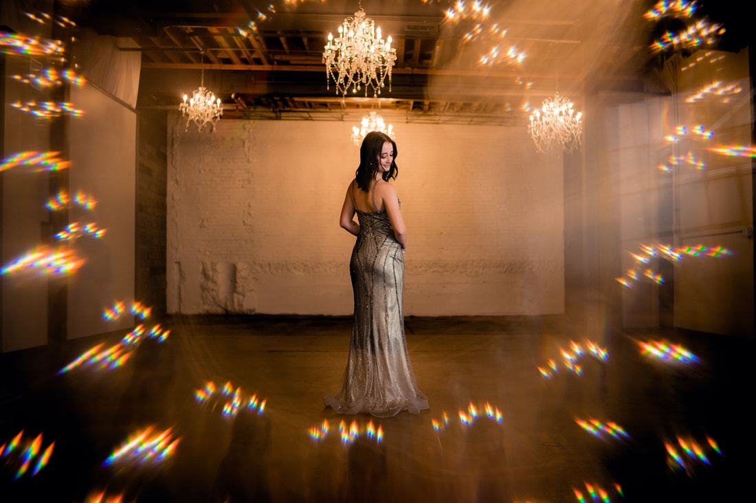 unique senior picture with silver prom dress and chandelier lights bokeh surrounding girl Denver Colorado