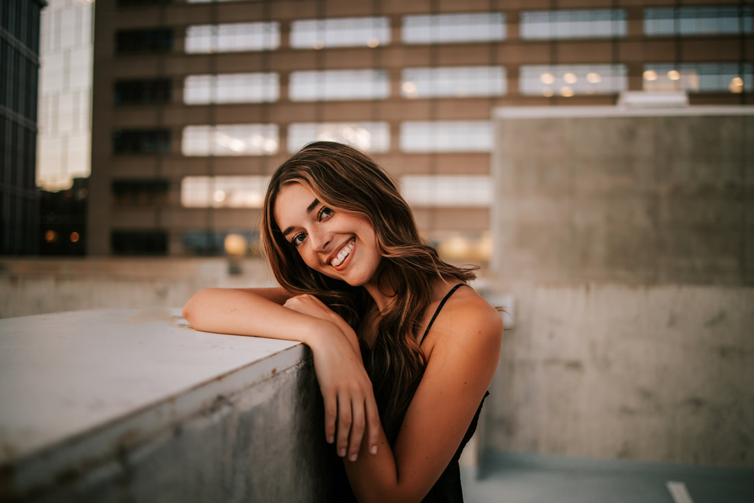 Beautiful girl relaxing on fence smiling for senior pictures