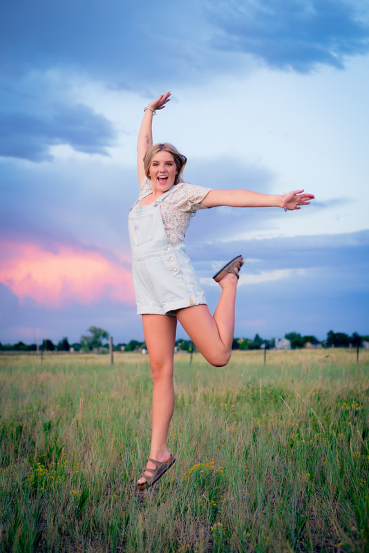 Blonde girl in overalls jumping for senior pictures 