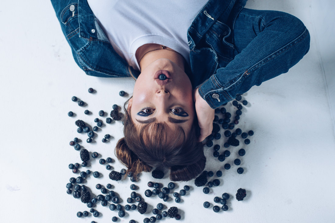 Girl with professional makeup surrounded by blueberries for senior pictures