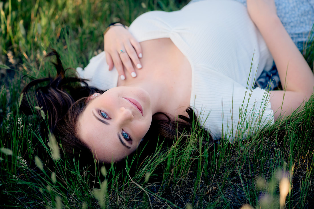 Blue eyed girl laying in a field for senior pictures