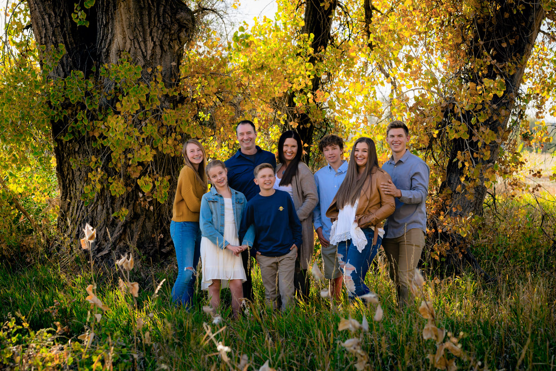 Family gathered in a green field smiling at the camera for a family photoshoot