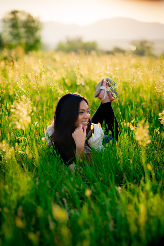 Girl laying in a field with her feet crossed behind her for senior pictures 