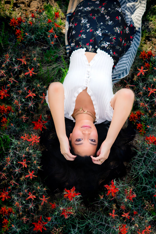 Girl laying in field with red flowers for senior pictures
