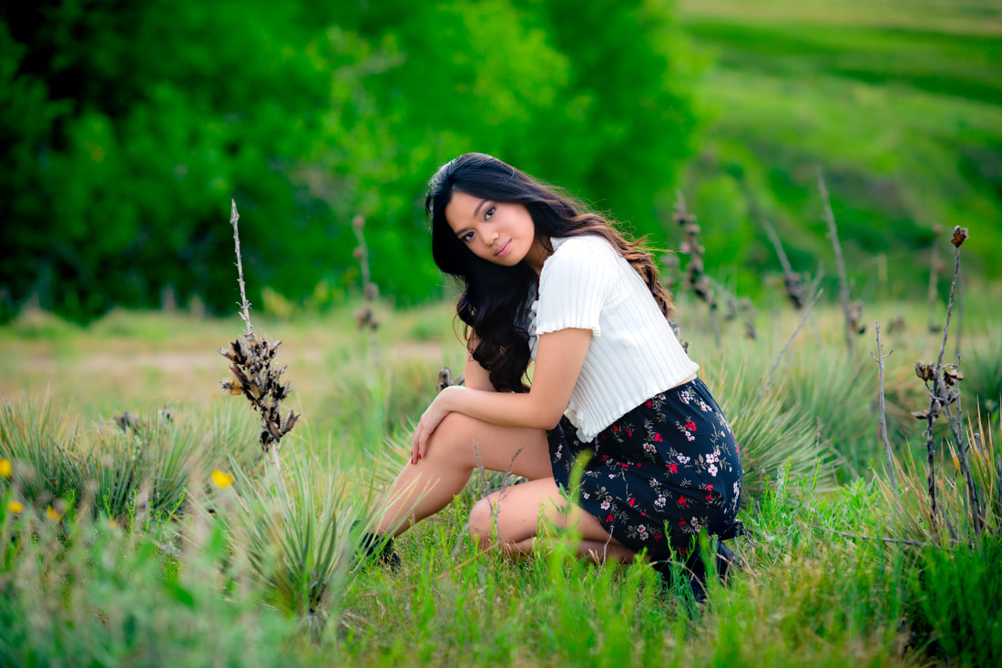 Girl with dark brown hair wearing a skirt in a field for senior pictures