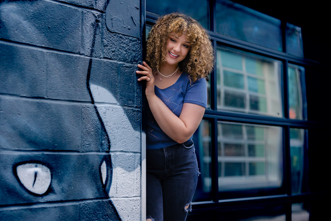 Girl with curly hair and graffiti in Denver urban city for senior photos