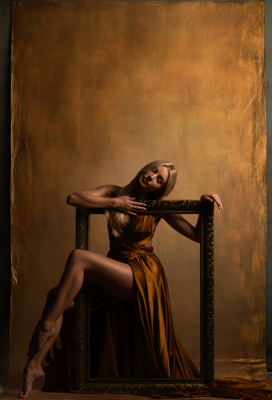 Girl in golden dress with picture frame interactive piece gold background Senior Photoshoot Broomfield Colorado 