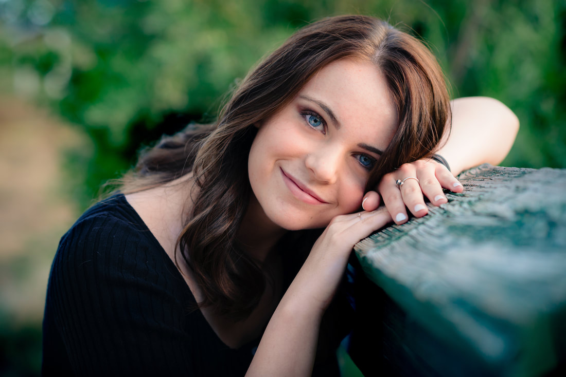 Girl leaning head on bridge smiling at camera for senior pictures
