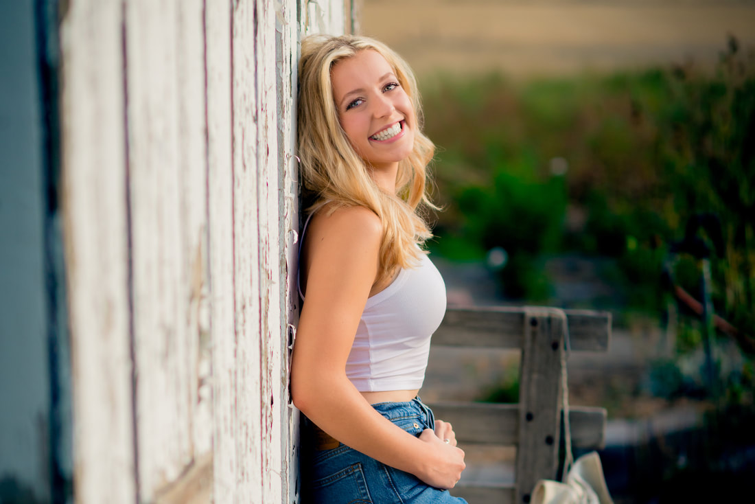 Blonde girl leaning against a barn for senior pictures