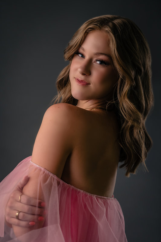Girl in pink dress smiling with glam makeup and professional styled hair for senior pictures Littleton Colorado Sarah Lindsay Photography