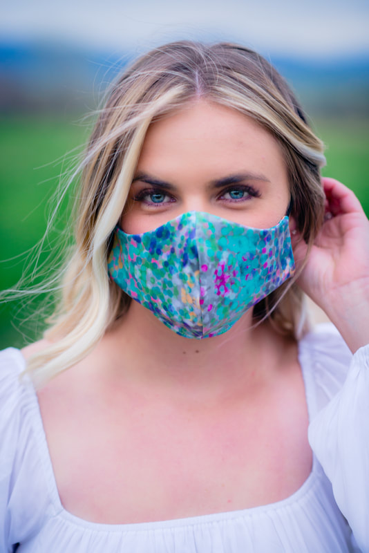 Girl in white dress with blue eyes wearing a turquoise face mask for senior pictures