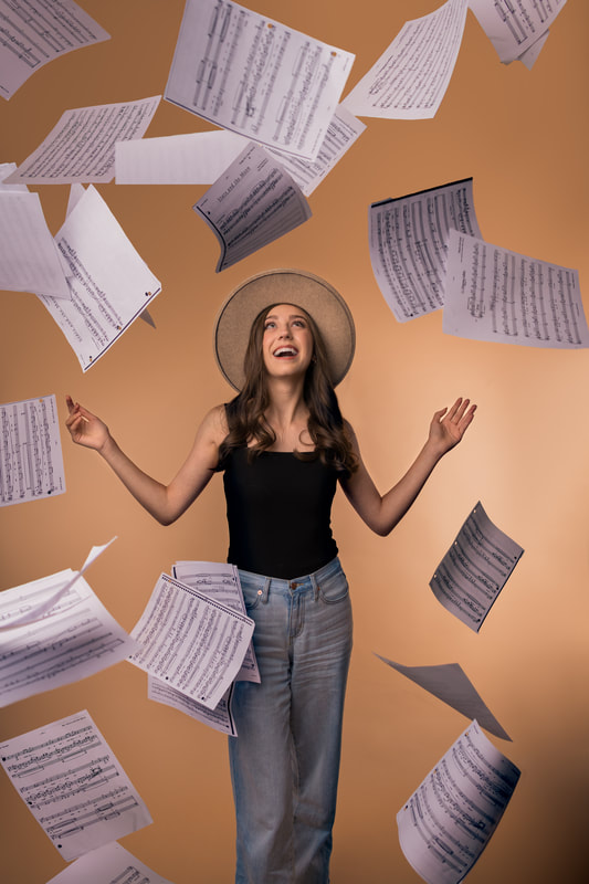 beautiful girl stands laughing while sheet music falls around her senior pictures ideas