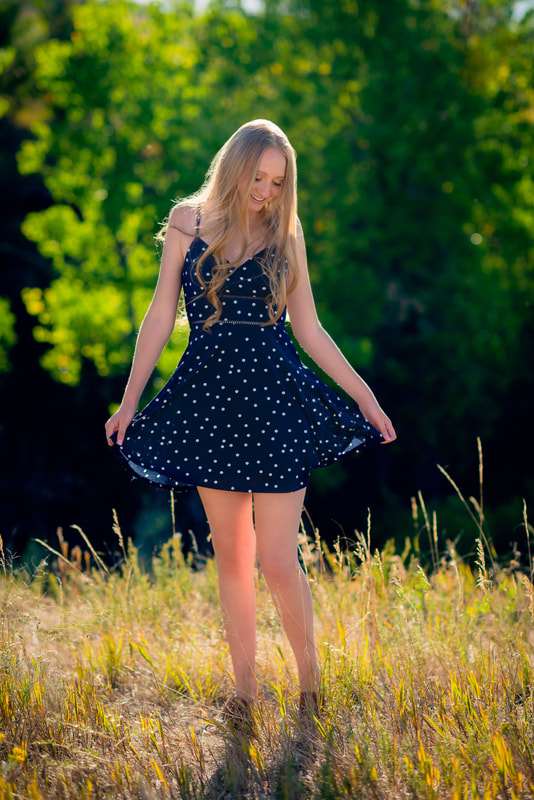 Girl twirling her dress standing in a field for senior pictures 