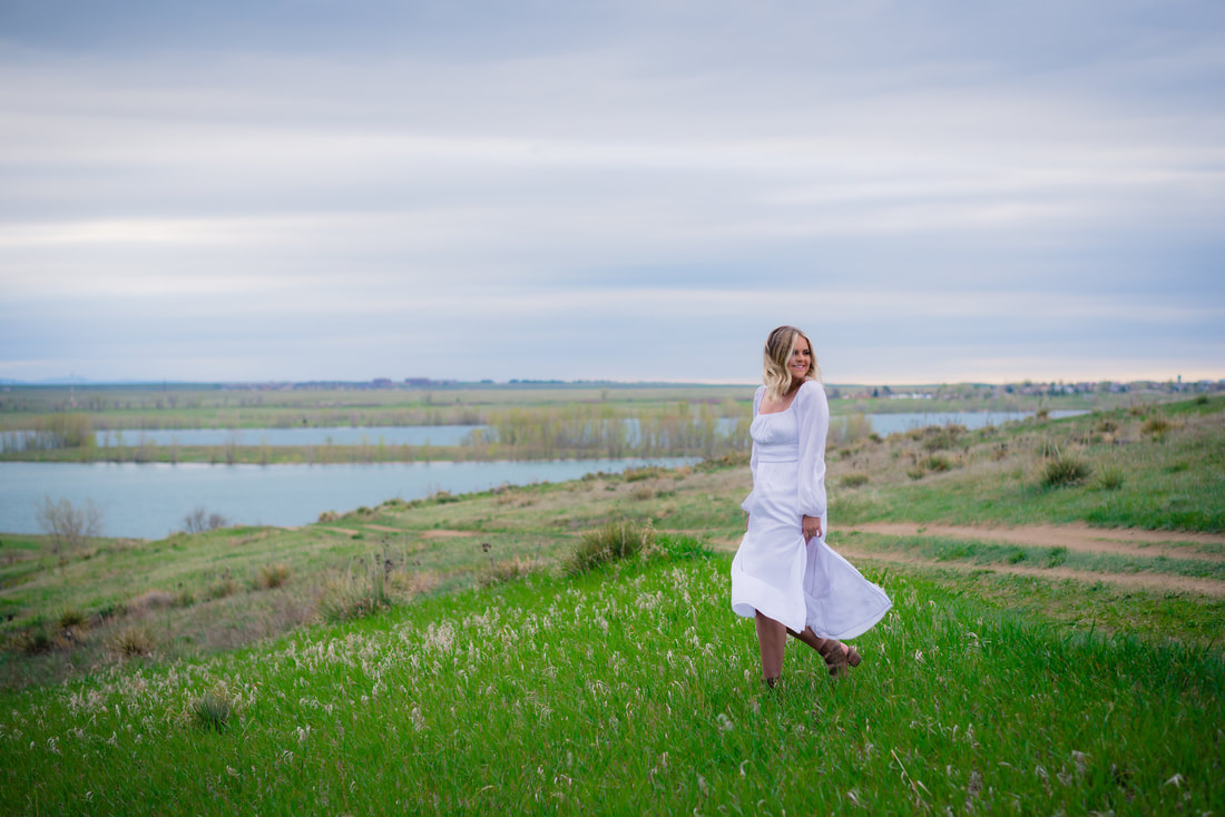 Girl in white dress walking in a green field for senior pictures 